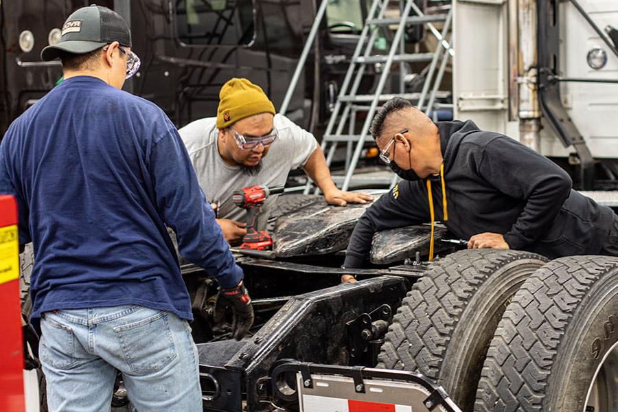 Three San Juan College students working on a diesel engine in a truck