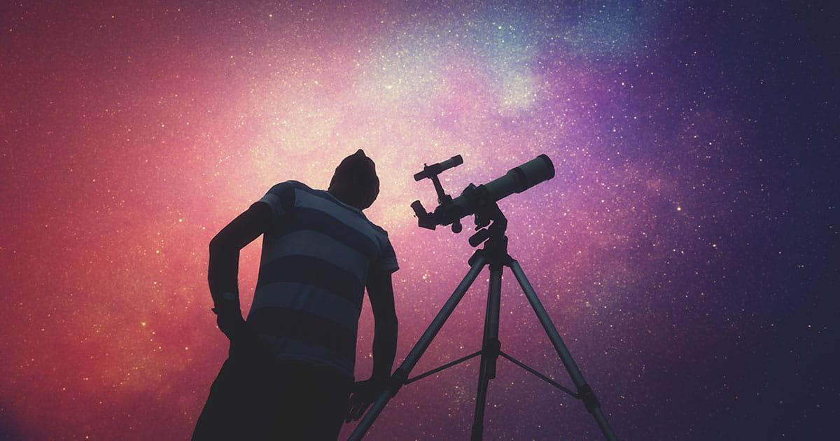 Man standing beside telescope